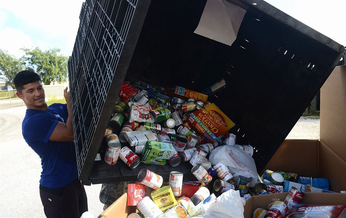 Волонтери пересипають продукти з великого контейнера в коробки для наборів